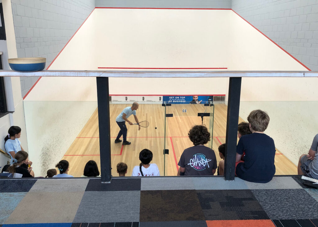 coach demonstrating squash to kids